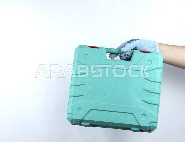 يد تمسك حقيبة معدات يدوية  , آلات ومعدات , أدوات بناء ,  هندسة معمارية , خلفية بيضاء .