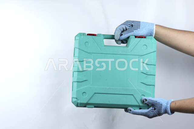 يد تمسك حقيبة معدات يدوية  ,أدوات بناء ,   آلات ومعدات , هندسة معمارية , خلفية بيضاء .