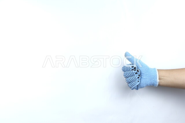 صورة مقربة ليد بقفازات زرقاء   ,ايماءات يد تدل على الموافقة  , رمز للاتفاق والقبول  , جيد , خلفية بيضاء .