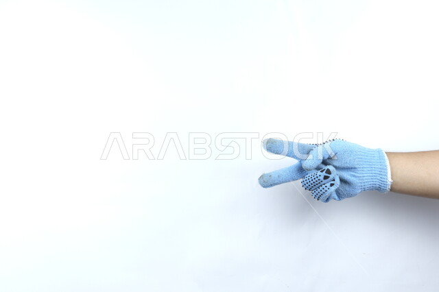 صورة مقربة ليد بقفازات زرقاء   ,خمسة اصابع , ايماءات يد تشير للعدد اثنين  , نجاح  , خلفية بيضاء .