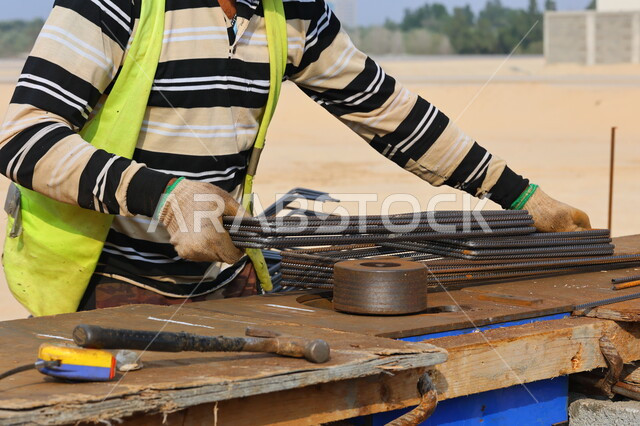 A close-up of a construction worker preparing metal construction rods, working and cutting iron for construction, construction equipment and tools, construction work, metal rods, installing steel