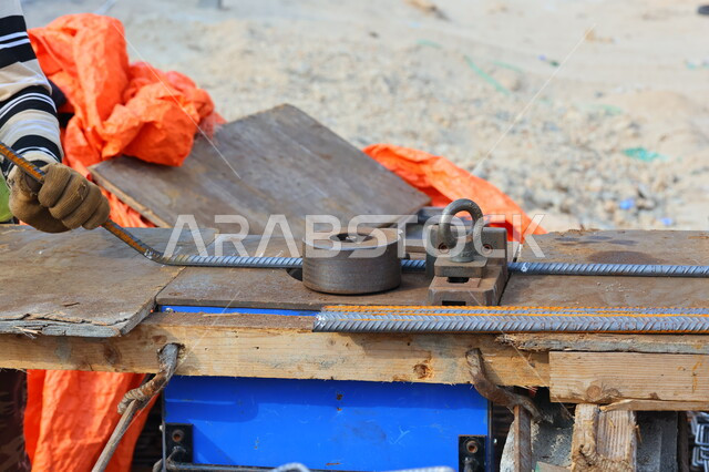 A close-up of a construction worker bending and cutting iron for construction, preparing metal construction bars, construction equipment and tools, construction work, metal bars, installing steel