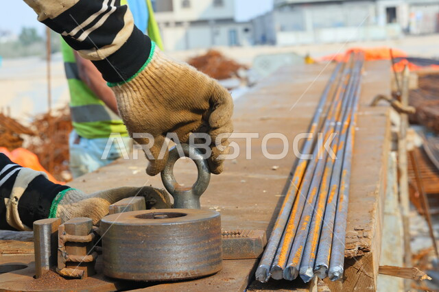 صورة مقربة لعامل بناء يقوم بتجهيز اسياخ البناء المعدنية، معدات وادوات البناء، عكف وقص الحديد للبناء، اعمال البناء، اسياخ معدنية، تركيب الحديد الصلب