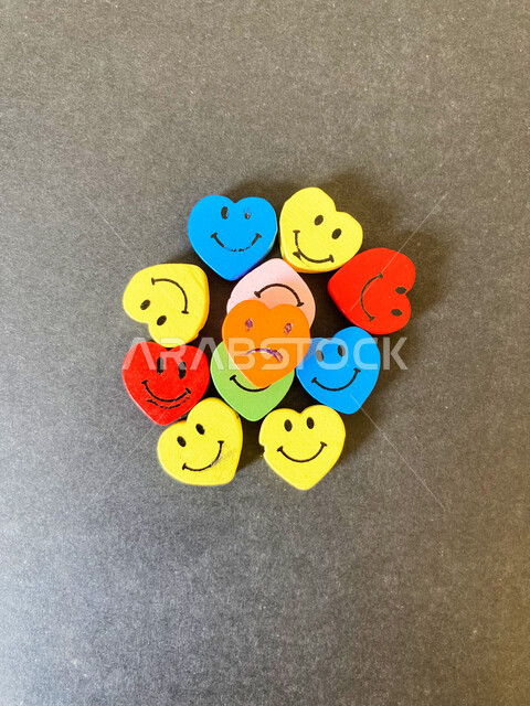 صورة مقربة لمجموعة من الوجوه المبتسمة والحزينة، دما صغيرة على شكل راس قلب، ميداليات، تصاميم واشكال ابداعية، خلفية رمادية