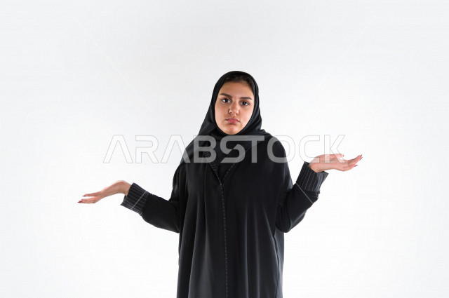 بورتريه لمرأه عربيه سعوديه خليجيه ترتدي العباءة والحجاب , إيماءات يدين تعبر عن قول لا أعلم, عدم المعرفه, الجهل بالأسباب, قلة العلم, الإستفهام عن شيء ما , خلفية بيضاء .