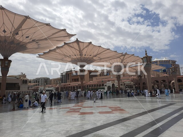 ساحة المسجد النبوي الشريف في المدينة المنورة في المملكة العربية السعودية، العبادة والتقرب الى الله ، الحرم النبوي الشريف، أماكن إسلامية مقدسة، المظلات الإلكترونية، تجمع المسلمون في المجمع الخارجي للمسجد النبوي في المدينة المنورة،  معالم دينية إسلامية.