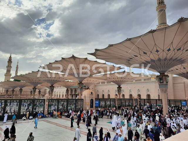 ساحة المسجد النبوي الشريف في المدينة المنورة في المملكة العربية السعودية، العبادة والتقرب الى الله ، الحرم النبوي الشريف، أماكن إسلامية مقدسة، تجمع المسلمون في المجمع الخارجي للمسجد النبوي في المدينة المنورة، المظلات الإلكترونية، معالم دينية إسلامية.