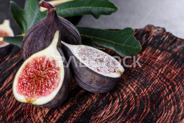 Close-up of a group of ripe figs, fresh fig fruit, harvest of figs, useful healthy fruits on a dark concrete background