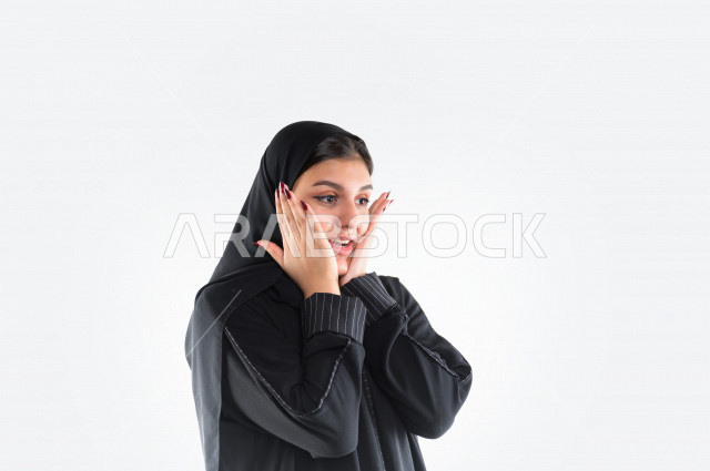 بورتريه لمرأة عربيه سعوديه خليجيه ترتدي العباءة والطرحة , إيماءات وجه ويدين تدل على الدهشه, التعجب, التفاجؤ من شيئ ما, الصدمه والذهول, الإستغراب , خلفية بيضاء .