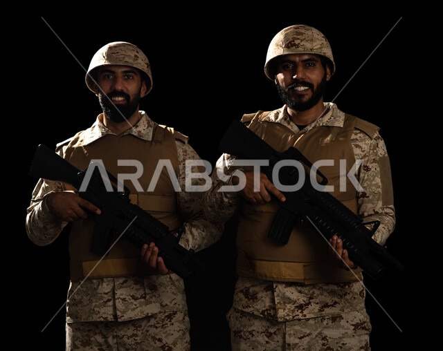التدريبات العسكرية والاستعداد للحرب، الوقوف بانضباط وحمل السلاح، الدفاع عن الوطن، بورتريه لعسكريان عربيان سعوديان خليجان يرتديان الزي العسكري، القوات المسلحة السعودية، خلفية سوداء