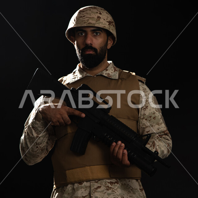 القوات المسلحة السعودية، بورتريه لعسكري عربي سعودي خليجي يرتدي الزي العسكري التقليدي ويقف بانضباط، حمل السلاح والدفاع عن الوطن، التدريبات العسكرية والاستعداد للحرب، خلفية سوداء