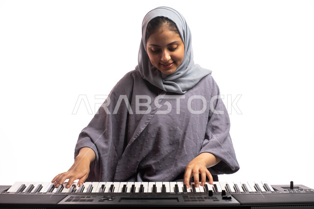 مواهب فنية موسيقية، بورتريه لامرأة خليجية سعودية عربية فنانة تقف امام آلة البيانو الموسيقية ويستمتع بالعزف، تقديم البرامج والفنون الموسيقية والفن المسرحي، قضاء الوقت بالعزف على آلة البيانو، الطرب والانشطة ترفيهية، خلفية بيضاء