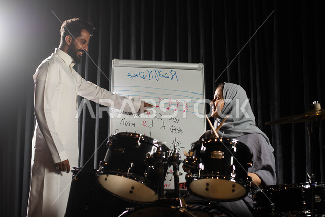 مدرس يقوم باعطاء جلسات تدريب تعليمية في الموسيقى، امرأة عربية خليجية سعودية تتعلم الاشكال الايقاعية الموسيقية، ممارسة هواية الطبل باستخدام آلة الطبل الالكترونية، تقديم البرامج والفنون الموسيقية والفن المسرحي، مواهب فنية موسيقية، انشطة ترفيهية