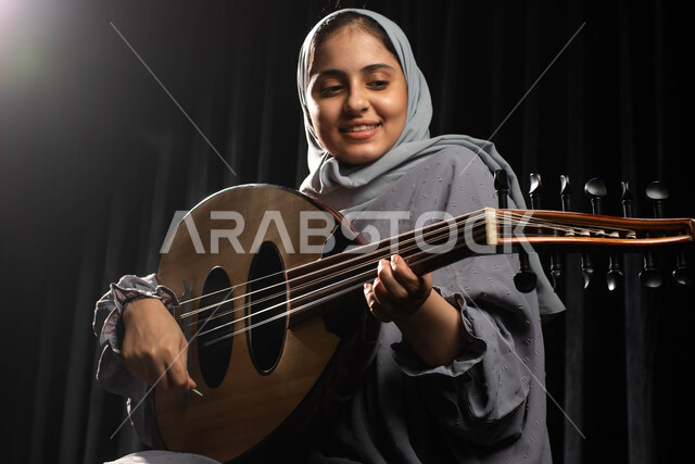ممارسة هواية العزف باستخدام آلة العود، مواهب فنية موسيقية، امرأة عازفة خليجية سعودية عربية محجبة تقدم البرامج والفنون الموسيقية والفن المسرحي، الإستمتاع بالعزف على الآلة الوترية، جلسة وناسة وطرب، انشطة ترفيهية