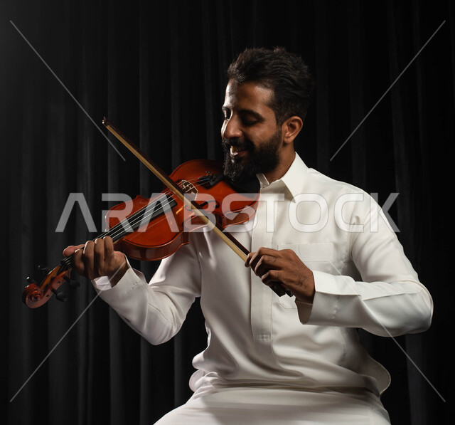 العزف على آلة الكمان، مواهب فنية موسيقية، رجل عربي خليجي سعودي فنان يمارس هواية العزف باستخدام آلة الكمان، تقديم البرامج والفنون الموسيقية والفن المسرحي، استخدام الآلات الموسيقية الوترية، جلسة وناسة وطرب، انشطة ترفيهية