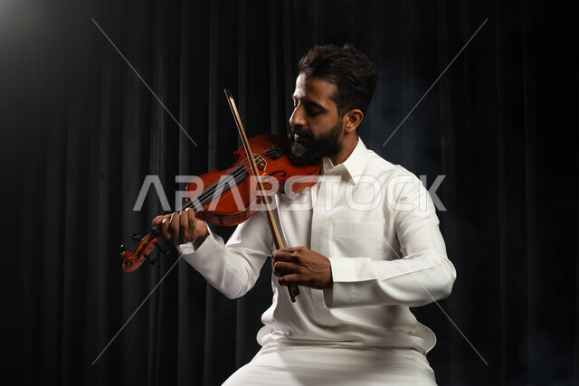 العزف على آلة الكمان، مواهب فنية موسيقية، رجل عازف عربي خليجي سعودي يمارس هواية العزف باستخدام آلة الكمان، تقديم البرامج والفنون الموسيقية والفن المسرحي، استخدام الآلات الموسيقية الوترية، جلسة وناسة وطرب، انشطة ترفيهية