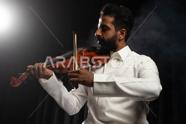 العزف على آلة الكمان، مواهب فنية موسيقية، رجل عازف عربي خليجي سعودي يمارس هواية العزف باستخدام آلة الكمان، تقديم البرامج والفنون الموسيقية والفن المسرحي، استخدام الآلات الموسيقية الوترية، جلسة وناسة وطرب، انشطة ترفيهية