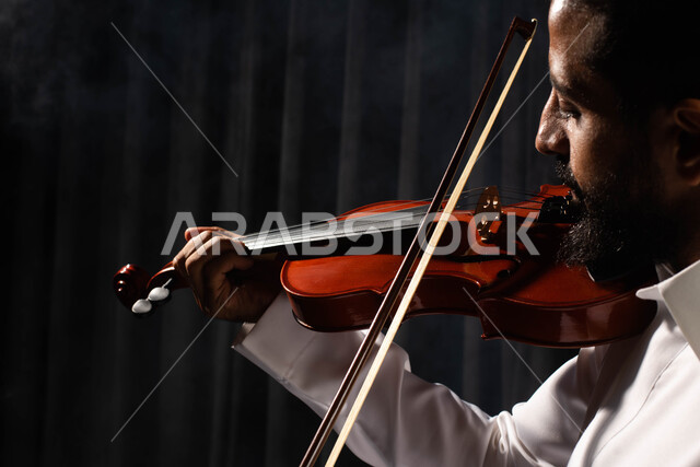 استخدام الآلات الموسيقية الوترية، ممارسة هواية العزف باستخدام آلة الكمان، تقديم البرامج والفنون الموسيقية والفن المسرحي، رجل عربي خليجي سعودي فنان يقوم بالعزف على آلة الكمان، مواهب فنية موسيقية، جلسة وناسة وطرب، انشطة ترفيهية