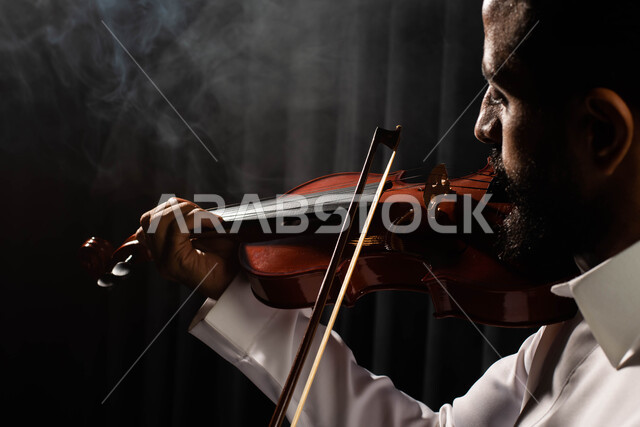 استخدام الآلات الموسيقية الوترية، ممارسة هواية العزف باستخدام آلة الكمان، تقديم البرامج والفنون الموسيقية والفن المسرحي، رجل عربي خليجي سعودي فنان يقوم بالعزف على آلة الكمان، مواهب فنية موسيقية، جلسة وناسة وطرب، انشطة ترفيهية