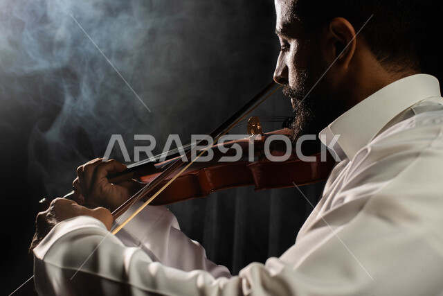 استخدام الآلات الموسيقية الوترية، ممارسة هواية العزف باستخدام آلة الكمان، تقديم البرامج والفنون الموسيقية والفن المسرحي، رجل عربي خليجي سعودي فنان يقوم بالعزف على آلة الكمان، مواهب فنية موسيقية، جلسة وناسة وطرب، انشطة ترفيهية