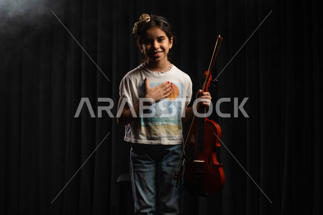 استخدام آلة الكمان الوترية في تقديم البرامج والفنون الموسيقية والفن المسرحي، فتاة فنانة سعودية خليجية عربية تقوم بالقاء التحية للجماهير على المسرح، ممارسة هواية العزف على آلة الكمان، مواهب فنية موسيقية