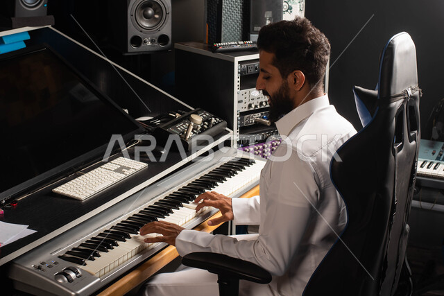 اجهزة تعديل الصوت والموسيقى، مواهب فنية موسيقية، رجل خليجي سعودي عربي فنان يجلس امام آلة البيانو الموسيقية ويستمتع بالعزف، تقديم البرامج والفنون الموسيقية والفن المسرحي، قضاء الوقت بالعزف على آلة البيانو