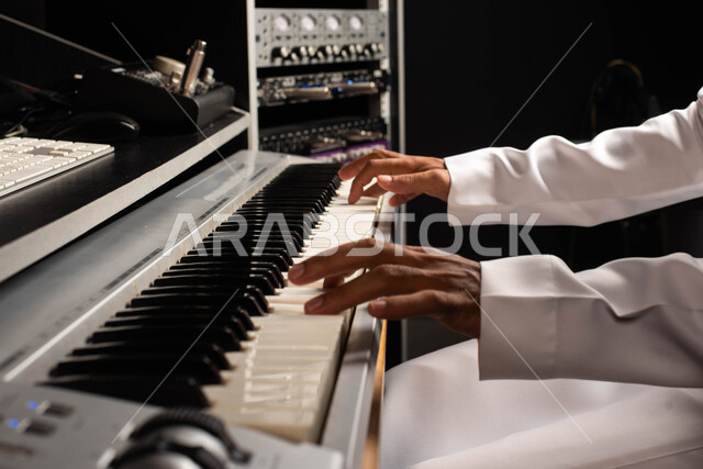 Presenting programs, musical arts and theatrical art, sound and music adjustment devices, musical talents, a close-up of a Saudi Arabian Gulf man, an artist who sits in front of a musical instrument and enjoys playing, spending time playing the piano