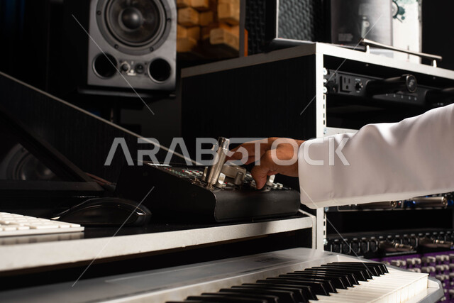 تقديم البرامج والفنون الموسيقية والفن المسرحي، اجهزة تعديل الصوت والموسيقى، مواهب فنية موسيقية، صورة مقربة لرجل خليجي سعودي عربي فنان يجلس امام آلة البيانو الموسيقية ويستمتع بالعزف، قضاء الوقت بالعزف على آلة البيانو