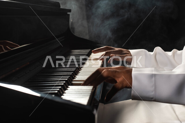 Spending time playing the piano, a close-up of a Saudi Arabian Gulf man, an artist who sits in front of a musical instrument and enjoys playing, musical artistic talents, presenting programs, musical arts, theatrical art, rapture and entertainment activit