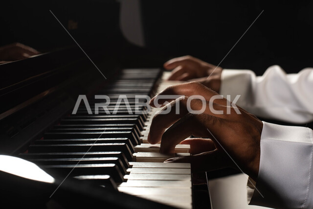Spending time playing the piano, a close-up of a Saudi Arabian Gulf man, an artist who sits in front of a musical instrument and enjoys playing, musical artistic talents, presenting programs, musical arts, theatrical art, rapture and entertainment activit