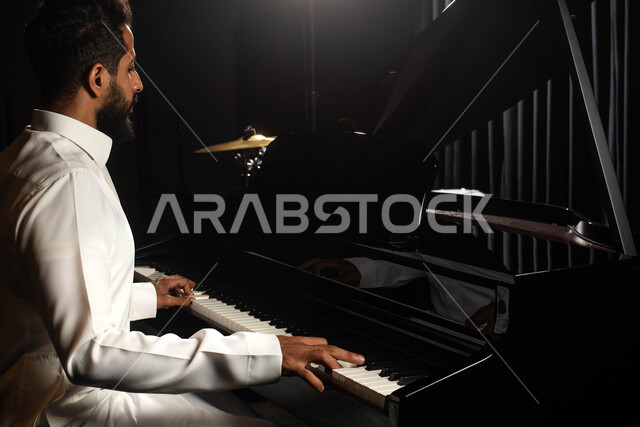 Musical artistic talents, a Saudi Arabian Gulf man, an artist who sits in front of the piano and enjoys playing, presenting programs, musical arts and theatrical art, spending time playing the piano, singing and entertainment activities