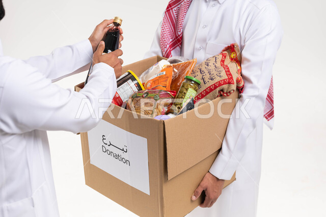 صورة مقربة لرجلان عربيان خليجيان سعوديان يقومان بتجهيز صندوق المواد الغذائية، التبرع لمشروع السلة الغذائية، توفير الطعام للمحتاجين، مبادرات وتبرعات انسانية خيرية، جمعيات اسلامية في السعودية، شهر رمضان، خلفية بيضاء