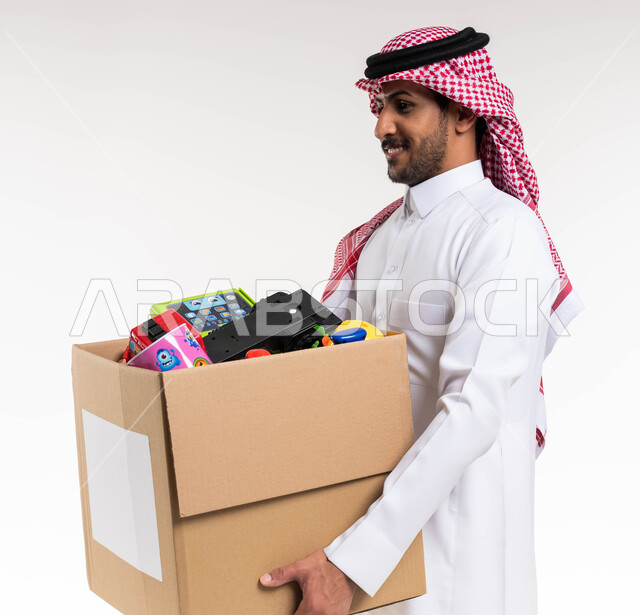 توفير الالعاب للاطفال المحتاجين، بورتريه لرجل عربي خليجي سعودي يحمل صندوق تبرعات مليء بالعاب الاطفال، مبادرات وتبرعات انسانية خيرية، جمعيات اسلامية في السعودية، خلفية بيضاء