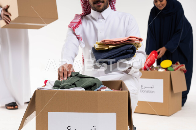 بورتريه لمجموعة من المتطوعيين العرب السعوديين الخليجيين يقومون بترتيب ملابس وهدايا العيد السعيد، جمع وتوزيع صناديق التبرعات للمحتاجين، مبادرات وتبرعات انسانية خيرية، جمعيات اسلامية في السعودية، خلفيه بيضاء
