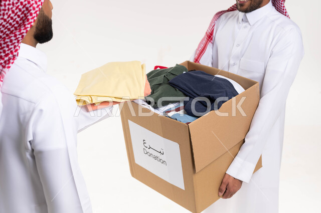 بورتريه لرجلان عربيان سعوديان خليجيان يتشاركان في تجهيز صندوق تبرعات الملابس الفائضه ، اهداء ملابس العيد للمحتاجين ، جمع وتوزيع التبرعات خيرية ،جمعيات خيرية ومبادرات انسانية ،  خدمة المجتمع السعودي المتعفف، خلفية بيضاء. 