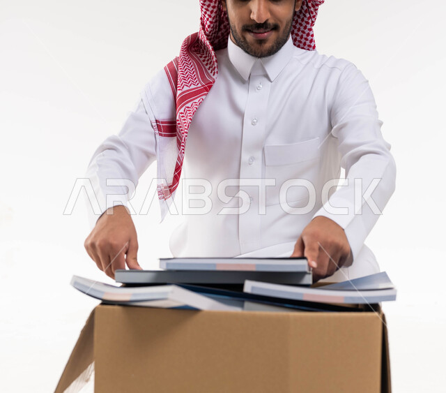 التبرع بالكتب الفائضة ، توفير الكتب التعليميه للمحتاجين ، بورتريه مقرب لرجل خليجي  عربي سعودي يرتدي الزي التقليدي  يقوم بوضع كتب في صندوق التبرعات ، اعادة وتدوير واستخدام الكتب ،اعمال خيرية اسلاميه  في السعودية ، خلفية بيضاء.