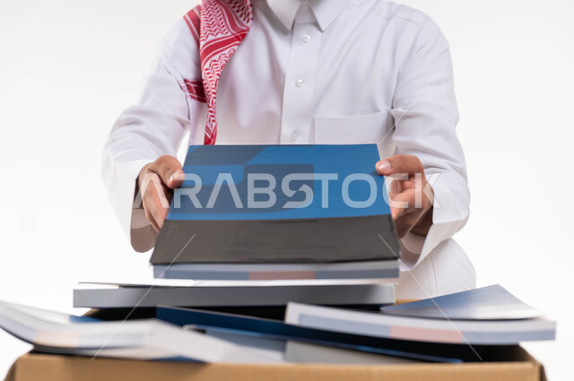 اعادة وتدوير واستخدام الكتب ، توفير الكتب التعليميه للمحتاجين ، بورتريه مقرب لرجل خليجي  عربي سعودي يرتدي الزي التقليدي  يقوم بوضع كتب في صندوق التبرعات ، التبرع بالكتب الفائضة ،اعمال خيرية اسلاميه  في السعودية ، خلفية بيضاء.