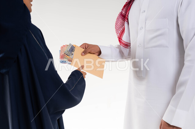  مساعدة واخراج زكاة المال للأسر المستحقة ، بورتريه مقرب لرجل عربي سعودي خليجي يرتدي الزي التقليدي السعودي يقدم زكاة الفطر لامرأة متعففة ، جمعيات خيرية في السعودية ، الصدقة والعطاء في شهر رمضان ، خلفية بيضاء.