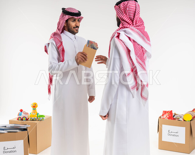 بورتريه لرجل عربي خليجي سعودي  بالزي  التقليدي السعودي يقدم زكاة الفطر للمحتاجين ، اخراج زكاة  المال للمحتاجين ، الصدقة والعطاء في شهر رمضان ، جمعيات خيرية في السعودية ، العبادة والتقرب الى الله ، خلفية بيضاء.