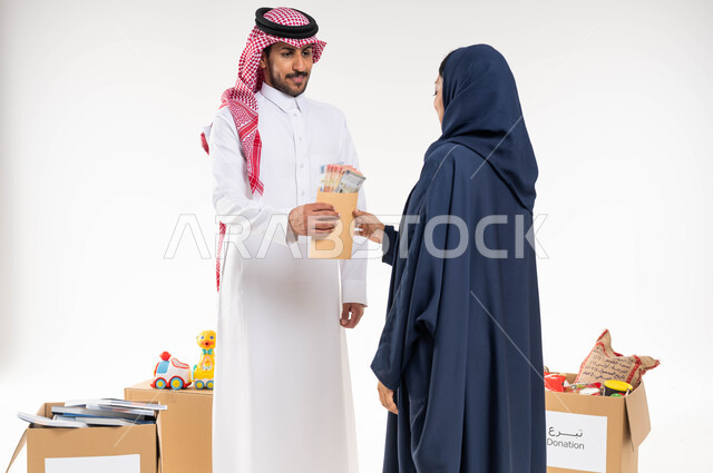 العطاء والصدقة في شهر رمضان ، بورتريه لرجل عربي سعودي خليجي يرتدي الزي السعودي التقليدي يقدم المساعدة لسيدة متعففة ، اخراج زكاة المال للمحتاجين ، جمعيات خيرية في السعودية ، خلفية بيضاء.
