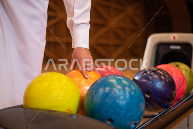 التسليه والترفيه ، رجل عربي خليجي سعودي، يرتدي الزي السعودي التقليدي يمارس لعبة البولينج ( الكردحه ) في أماكن ترفيهية ، أنشطة رياضية ترفيهية ،  ملعب البولينج ، قضاء أوقات ممتعة