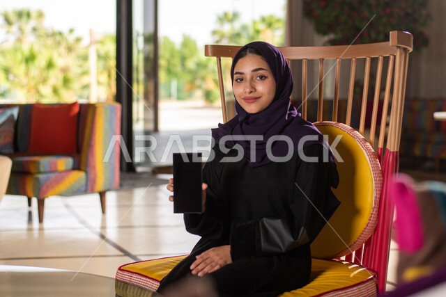 عرض شاشة سوداء فارغة ، تصفح الانترنت  واستخدام تقنيات حديثة ، انجاز مهام العمل ، شابة عربية سعودية خليجية تستخدم الحاسوب المحمول ، العمل عن بعد ، التواصل مع  العملاء ، التسويق الالكتروني