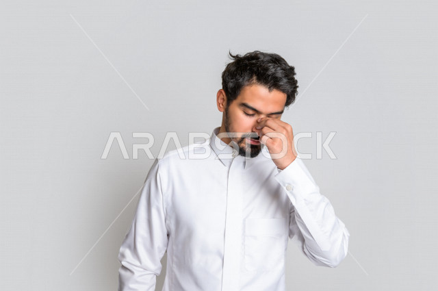 بورتريه لرجل عربي سعودي خليجي يرتدي الثوب السعودي, ايماءات وجه ويدين تدل على الشعور بالحزن والإحباط, الرغبه بالبكاء, الندم على شيء ما, الخساره والفشل , خلفية بيضاء .