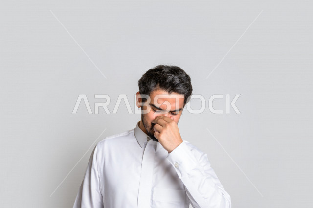 بورتريه لرجل سعودي خليجي متعب بإيماءات الوجه تدل على النعاس ، خلفية بيضاء