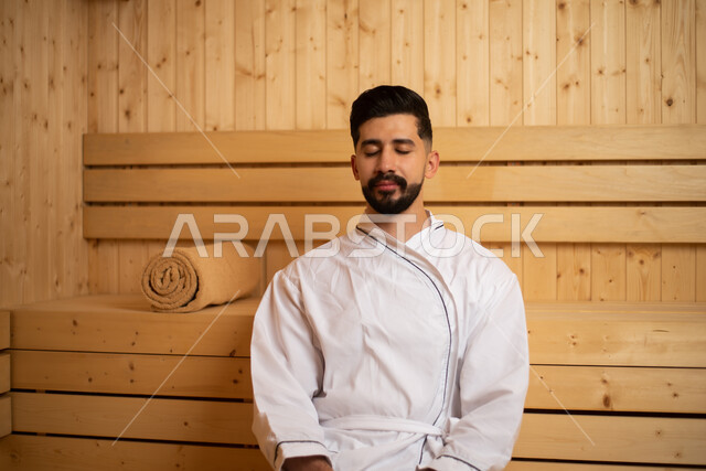 Health resorts for health and physical care, a young Saudi man enjoying himself in one of the spa centers in Saudi Arabia, getting a rest and relaxation in the resort facilities, relaxation in the sauna room, attention and care for appearance, luxury and 