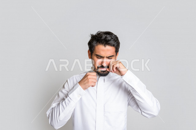 بورتريه لرجل عربي سعودي خليجي يرتدي الثوب السعودي, ايماءات وجه ويدين تدل على الشعور بالحزن والإحباط, الرغبه بالبكاء, الندم على شيء ما, الخساره والفشل , خلفية بيضاء .