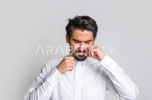 بورتريه لرجل عربي سعودي خليجي يرتدي الثوب السعودي, ايماءات وجه ويدين تدل على الشعور بالحزن والإحباط, الرغبه بالبكاء, الندم على شيء ما, الخساره والفشل , خلفية بيضاء .