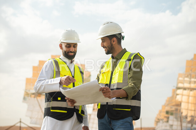 محطات الطاقة الشمسية المتجددة، مهندسان عربيان خليجيان سعوديان يشرفان على محطات الطاقة الشمسية في السعودية، إرتداء خوذة وسترة الحماية الخاصة بالعمل، مخططات وتصاميم هندسية، حوارات ونقاشات عمل ،  الواح وستلايت انتاج الطاقة الكهربائية , تطور التقنية .