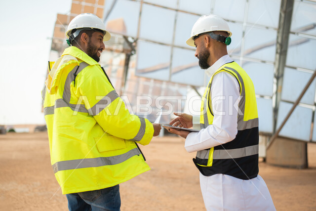 حوارات ونقاشات عمل ، مهندسان عربيان خليجيان سعوديان يشرفان على محطات الطاقة الشمسية في السعودية، إرتداء خوذة وسترة الحماية الخاصة بالعمل، مخططات وتصاميم هندسية،  محطات الطاقة الشمسية المتجددة، الواح وستلايت انتاج الطاقة الكهربائية , تطور التقنية والتكنولو