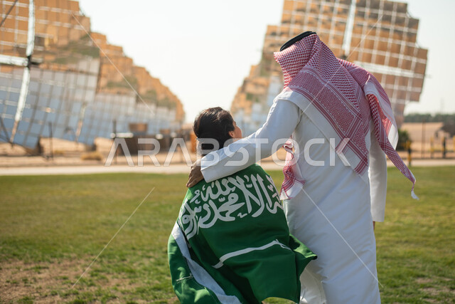 محطات توليد الكهرباء عبر الطاقة الشمسية، صورة من الخلف لفتاة تضع علم المملكة العربية السعودية على ظهرها ،الاحتفال باليوم الوطني السعودي 92 ، مستقبل السعودية، يوم العلم  ، ستلايت وألواح الطاقة الطبيعية المتجدده ، رؤية ومشاريع مستقبلية جديدة .